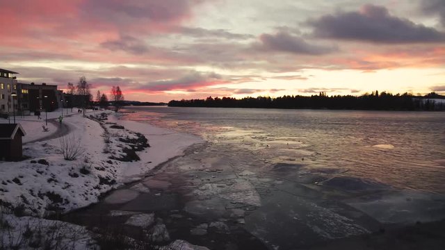 Time lapse of river in sunset, with blocks of ice floating down the stream.