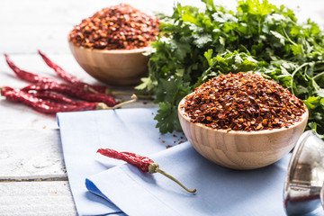 Dried and crushed chili peppers in wooden bowles with parsley herbs