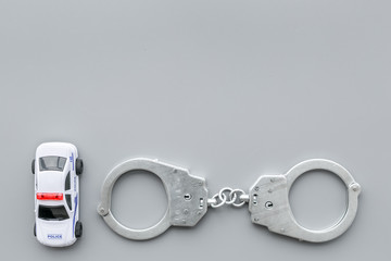 Police concept. Police car toy and handcuff on grey background top view space for text