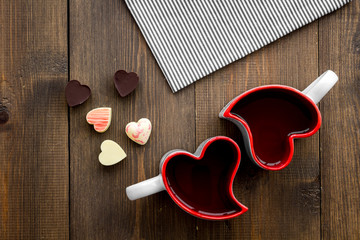 Valentine's day concept. Heart-shaped mugs and sweets on dark wooden background top view copy space