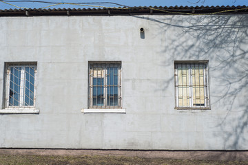 A gray building with old windows and rusty bars on them