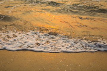 sea wave foam at the sandy shore close-up in the evening