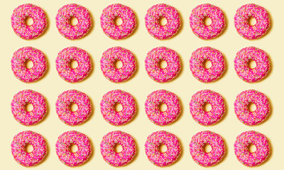 Top view of several rows of bright pink sweet donut with pink icing and multi-colored powder on a multicolored background. 