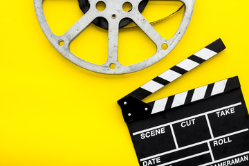 Filmings concept. Clapperboard and film stock on yellow background top view space for text