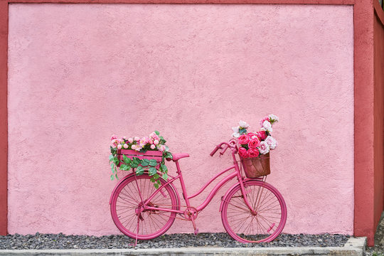 Bright pink bike with flowers in its baskets outdoors