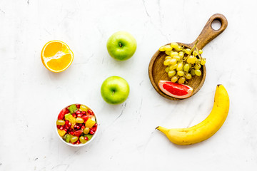 Healthy diet concept. Fruit salad near fresh fruits on white background top view