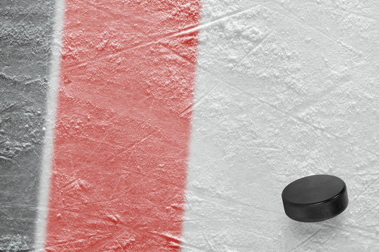 Hockey puck and fragment of the ice arena with black and red lines