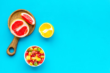 Food rich by vitamins and fiber. Healthy food. Fruit salad near fresh fruits on blue background top view space for text