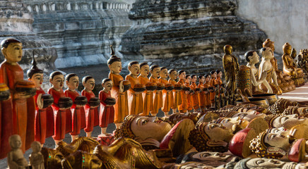 carved wooden statues of monks carrying their bowls to collect alms all lined up at the floating...