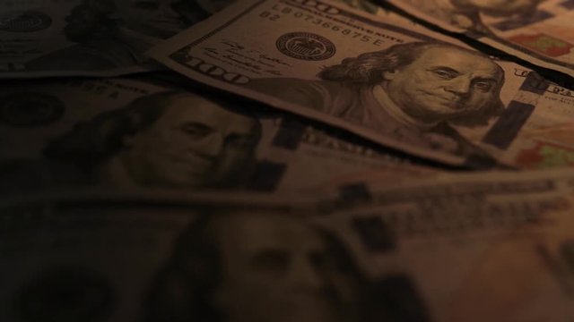 Pan around hundred dollar bills, light to dark gradient.  Entire frame is filled.