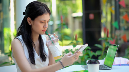 Beautiful woman drinking beverage and used smartphone