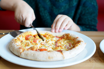 girl cuts pizza with a knife