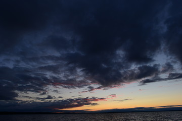 Dark clouds of the twilight sky over the water surface of the lake