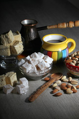 Fototapeta na wymiar A mug of coffee and different oriental sweets: turkish delight, halva, almond and pistachio