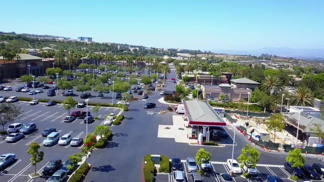Aerial fly through of a shopping mall parking lot over a gas station