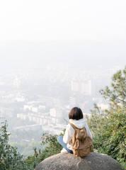 Fototapeta na wymiar girl with backpack on peak of foggy mountain.