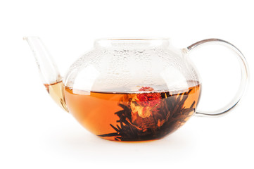 A cup of tea with fresh green and black tea leaves is isolated on a white background with copy space. Flower tea in a glass teapot