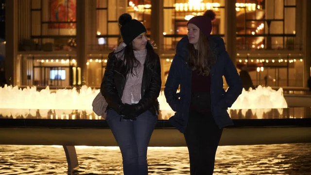 Two girls have an amazing night in New York while sitting at a fountain