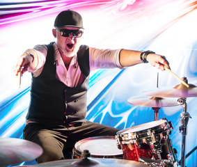 Emotional drummer playing on drum set on stage in the color light