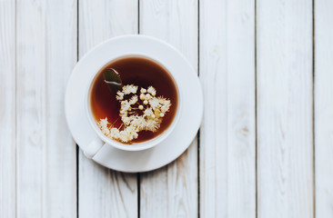 Herbal medicine concept. White cup and dish of linden tea on grey background. Rustic. Top view.