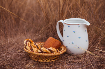 White jar and baked buns in the field. Countryside style meals with jar of milk and homemade pastry with space for text