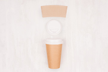 Coffee kraft paper cup with blank label, cap on light wood board, top view. Mockup for branding identity, advertising and design concept.