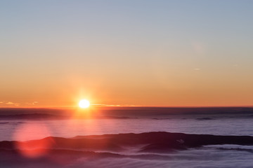 Beautiful sunset over a valley filled by fog with mountains and hills