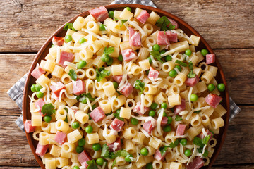 Portion of Ditalini pasta with green peas, ham and cheese closeup on a plate. horizontal top view