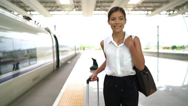Happy Asian traveler smiling going on train travel in business class. Beautiful woman with hand luggage leaving on luxury transport. Businesswoman commuting to work in the morning. Shaky cam