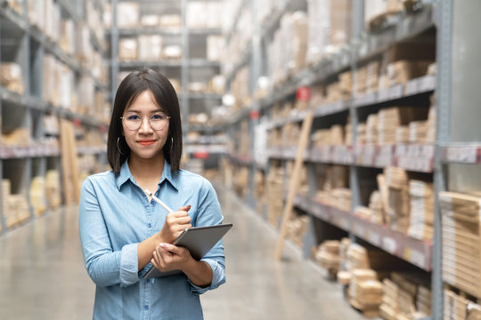 Young attractive asian worker, owner, entrepreneur woman holding smart tablet looking at camera with concept efulfillment service business warehouse management stock online. Asian sme merchandise.