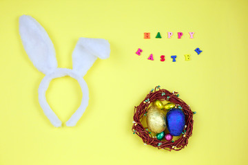 Happy easter with adorable bunny ears on a bird nest with colorful eggs against on yellow background