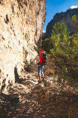 Traveler woman climbs along narrow mountain gorge