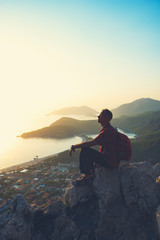 Traveler relaxes on a cliff and admires the amazing sea bay
