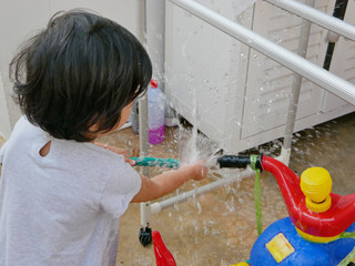 Little Asian baby girl playing water and learning to wash her plastic big bike