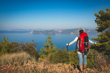 Traveler woman with backpack stands on the cliff
