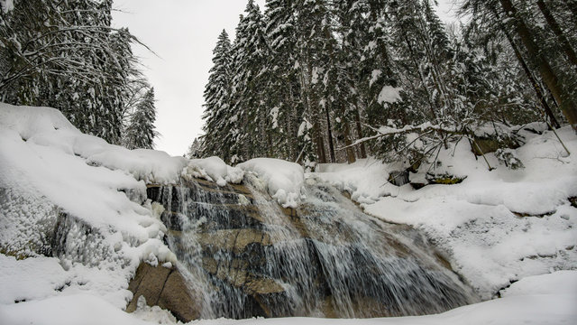 Wasserfall im Winter mit schnee und Wald in Tschechen Harrachov