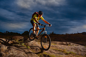 Obraz na płótnie Canvas Cyclist Riding the Mountain Bike on Rocky Trail in the Evening. Extreme Sport and Enduro Biking Concept.