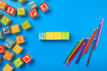 News. Wooden colorful alphabet blocks on blue background, flat lay, top view.
