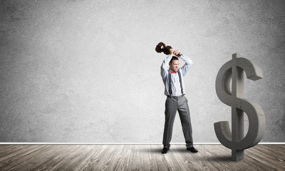 Determined banker man in empty concrete room breaking dollar figure