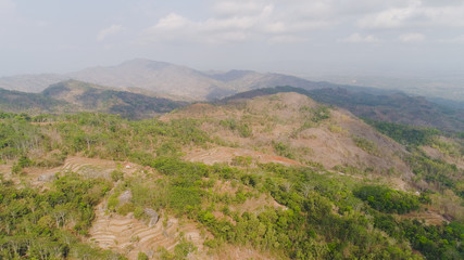 Fototapeta na wymiar mountain landscape high cliffs mountains covered with green tropical forest. aerial view mountain forest with large trees and green grass. tropical landscape in asia Jawa, Indonesia