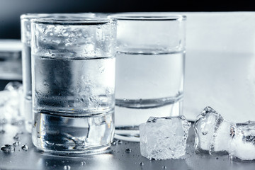 Cold vodka in shot glasses on a black background.