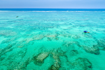 blue sail boat in emerald lagoon in tropical island