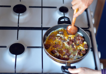 Top view of a hand which is cooking omelette with Turkish sausage