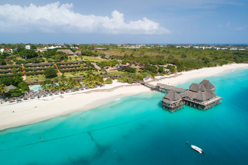view to clouds and beach with wooden restaurant on Zanzibar island - obrazy, fototapety, plakaty