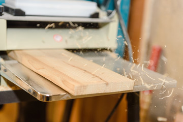 Fototapeta na wymiar Wood processing on the machine. Flies shavings. Level the board. Joiner's tool.