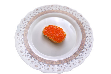 Sandwich with butter and red caviar in the middle of a large plate, close-up