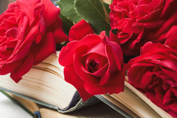 Red roses on an open book on a light stone background. The concept of romantic literature. Flat lay, top view