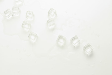 Cubes of ice and spilled water on a light background