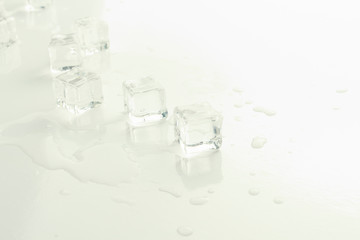 Cubes of ice and spilled water on a light background