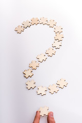 Hand holding the last piece of question mark. Question mark made from puzzle pieces on white background - 246123800